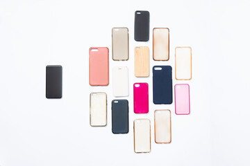Obraz premium Pile of multicolored plastic back covers for mobile phone on white background. Choice of smart phone protector accessories. A lot of silicone phone backs or skins next to smart phone