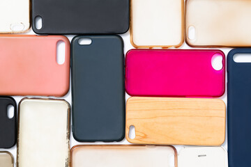 Pile of multicolored plastic back covers for mobile phone. Choice of smart phone protector accessories on white background. A lot of silicone phone backs or skins next to each other