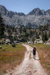 Fototapeta na wymiar Senderista caminando por un camino en el parque nacional de aiguestortes con vistas a las montañas 