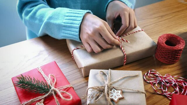 Woman wrapping christmas presents on wooden desk.