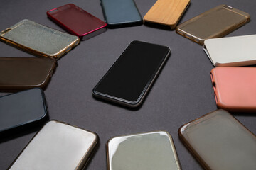 Pile of multicolored plastic back covers for mobile phones on black background with a phone on the side