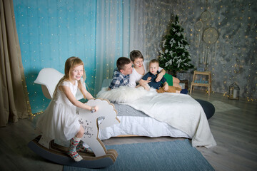 Naklejka premium Family in home interior of Christmas and New Year. parents and children are happy together at christmas. Girl riding a toy horse at home
