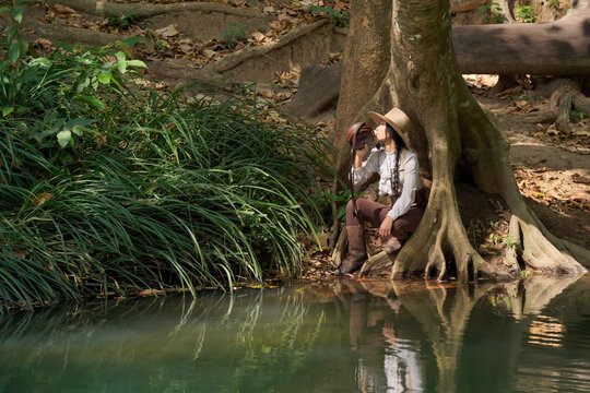 A cowgirl relaxes by a river in summer.
