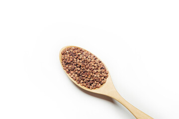 Top view of the wooden spoon filled with uncooked buckwheat isolated on the white background