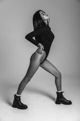 Photoshoot of a young brunette. A girl in a black bodysuit and black shoes. Fitness exercises....
