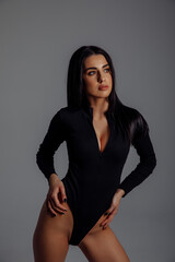 Naklejka premium Photoshoot of a young brunette. A girl in a black bodysuit and black shoes. Fitness exercises. White background.