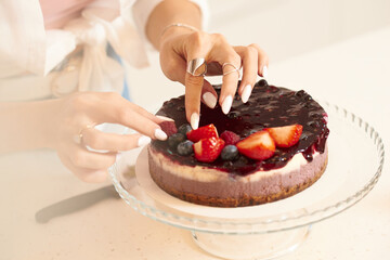 The girl decorates the cake. Close hands. Details
