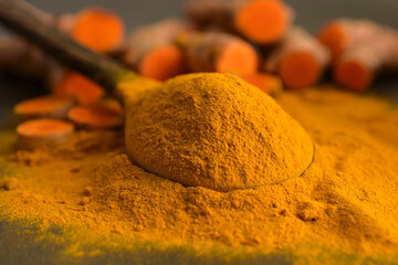 Turmeric powder and fresh turmeric (curcumin) on black background,For cooking.