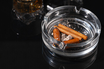 Ash tray full of cigarette butts on black background