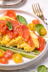 Fried eggs with green asparagus and salmon, cherry tomatoes and fresh spinach.