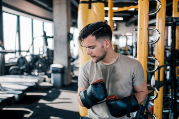 Young man with boxing gloves on a break from workout at the gym.