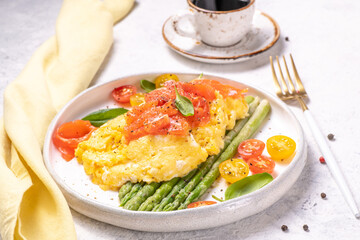Fried eggs with green asparagus and salmon, cherry tomatoes and fresh spinach.