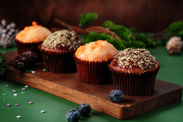 Chocolate and orange cupcakes on a wooden board with Christmas decorations. Sweet muffins on the table