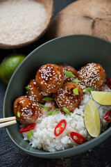 Close-up of a green bowl with rice and roasted meatballs in sweet sauce, studio shot, selective focus