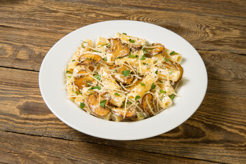 Pasta with mushrooms, white wine and leeks in white plate on a rustic table. Close up. 