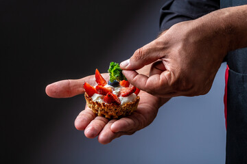 Close up master chef hands making a delicious strawberry tarts. Fruit dessert tarts with cheese cream