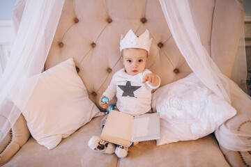 a little boy sits on the couch with a crown on his head