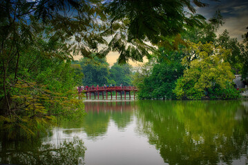Fototapeta na wymiar Bridge in Hanoi, Vietnam viewed from a distance surrounded by lush greenery and lake 