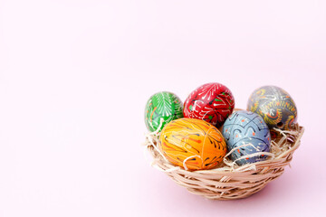 Easter eggs painted in bright colors on a pink background with copy space