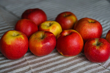 Red apples are on a mottled light canvas, foreshortening on the side