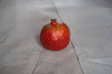 Red pomegranate lies on a gray canvas