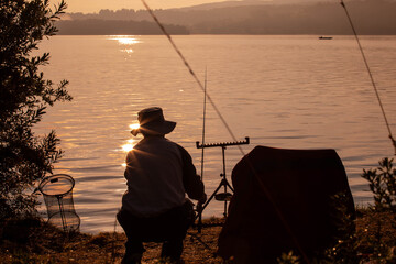 Fisherman on the lake shore preparing for fishing. Early morning light