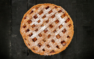 Delicious homemade apple pie on black wooden table. Thanksgiving autumn dinner flat lay food.