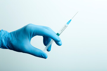 Doctor's hand with a syringe in the hospital. A hand in a medical glove holds a syringe with a...