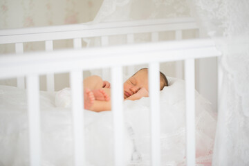 Fototapeta na wymiar newborn sleeps in white crib. concept of healthy children's sleep.