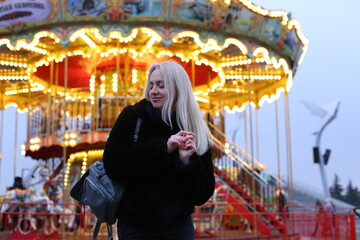 Blonde in black fur coat near the Christmas carousel.