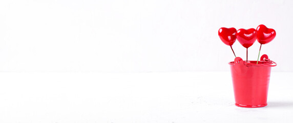 Decorative hearts in the small red bucket against the white background. Wide banner. Valentine card