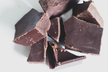 Broken bitter dark chocolate on a white background.