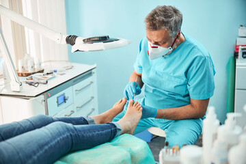 Obraz premium Unrecognized female patient sitting on the medical chair at the pedicure procedure in medicine center