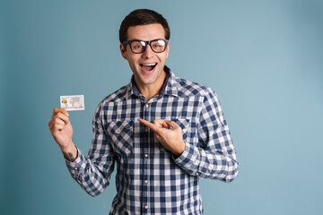 Happy smiling young man showing credit card