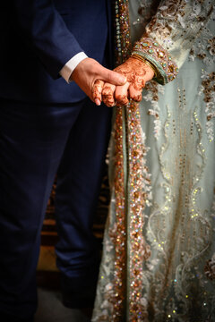 Pareja de novios en su matrimonio dándose la mano con los vestidos típicos de la cultura con henna en las manos