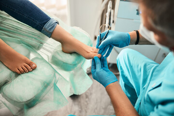 Female patient visiting podiatrist with pain on feet and toes - obrazy, fototapety, plakaty