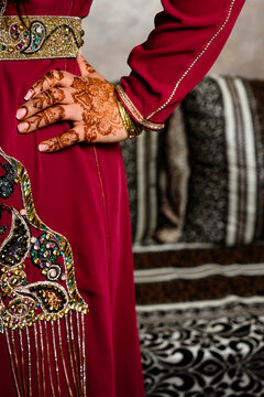 Mano de mujer típica cultura india o arabe con vestido rojo y henna en las manos en interior con decoración cultural