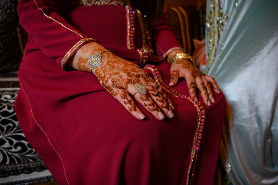 Manos de mujer con anillos y joyas diseño en con henna vestido típico indio o arabe de color rojo y decoración