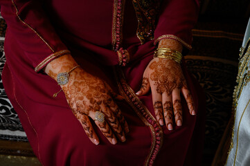 Manos de mujer con anillos y joyas diseño en con henna vestido típico indio o arabe de color rojo y decoración