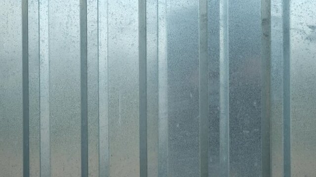 Metal steel fence from iron of silver color, closeup view. Aluminum and zink striped covering. Facade, exterior outdoors on street.
