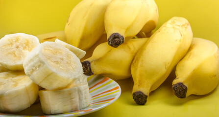 Close up de banana cortada no prato e bananas maduras com casca