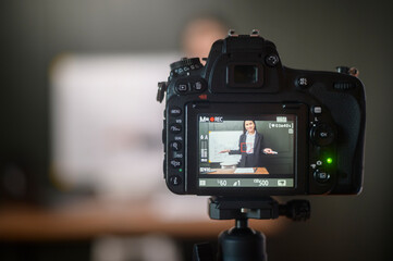 A young woman teacher is using a camera for recording online lesson during quarantine, online education , distance learning concept..