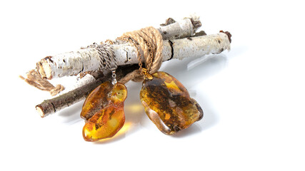 Two amazing sparkling old yellow and green Baltic amber pendants on the birch twigs. Isolated...