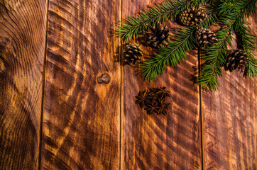 Christmas cones and branches on wooden boards.