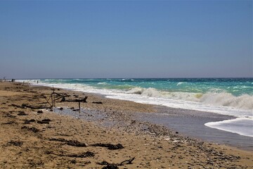 evocative image of a sandy beach with a sea of many colors and clear skies
