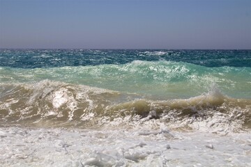 evocative image of a sandy beach with a sea of many colors and clear skies

