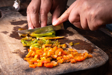 man cutting bell pepper a wooden board
