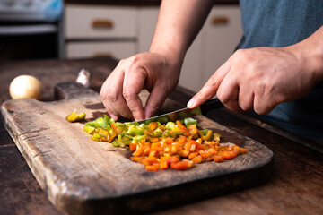 man cutting bell pepper a wooden board
