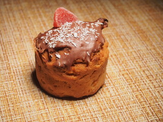 One handmade cupcake decorated with chocolate icing, coconut chips and marmalade.