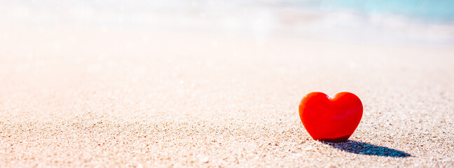 Romantic symbol of red heart on the sand beach